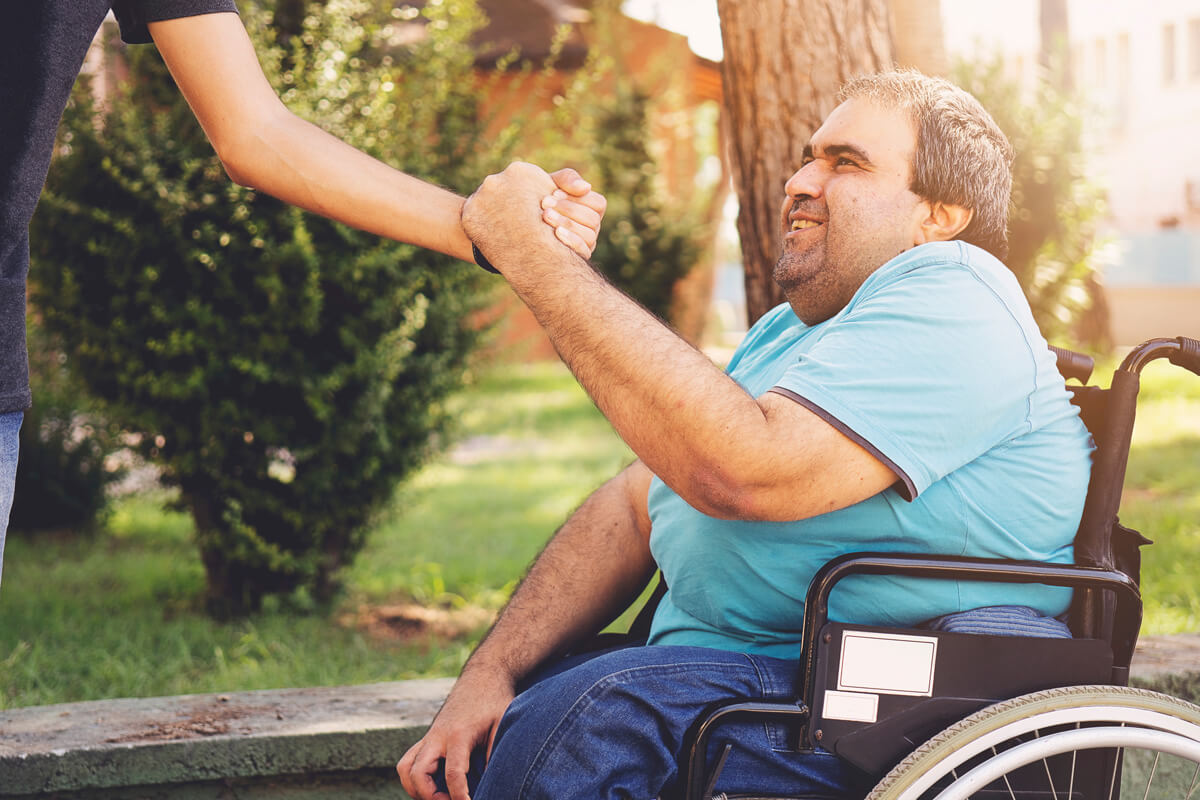 Man in wheelchair shaking hands with support worker